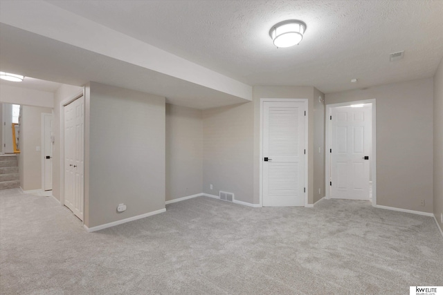 basement with a textured ceiling and light carpet