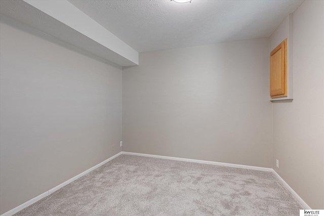 empty room with light colored carpet and a textured ceiling