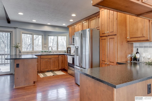 kitchen with tasteful backsplash, a kitchen island, kitchen peninsula, sink, and appliances with stainless steel finishes