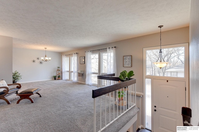 entrance foyer with carpet, an inviting chandelier, and a textured ceiling