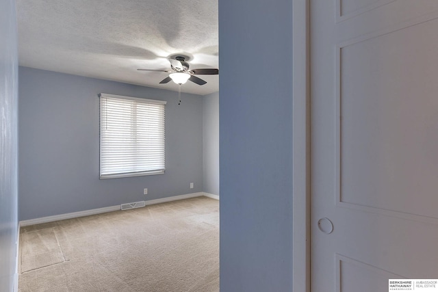 empty room with light carpet, ceiling fan, and a textured ceiling