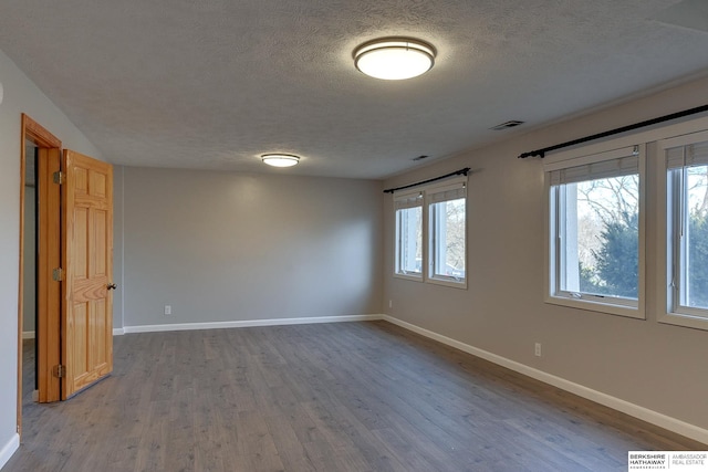 empty room with hardwood / wood-style flooring and a textured ceiling