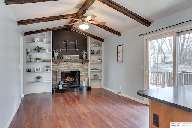 unfurnished living room with ceiling fan, dark wood-type flooring, built in features, a fireplace, and vaulted ceiling with beams