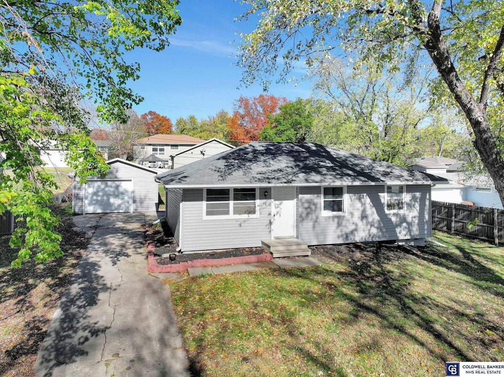 view of front of home with a garage, a front yard, and an outbuilding