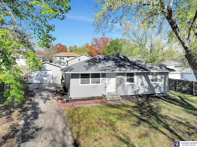 view of front of home with a garage, a front yard, and an outbuilding