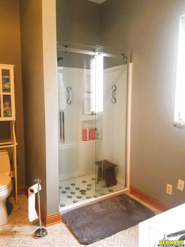 bathroom with a shower with shower door and toilet