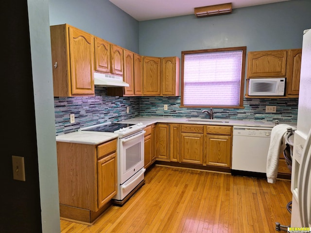 kitchen featuring sink, backsplash, white appliances, and light hardwood / wood-style flooring