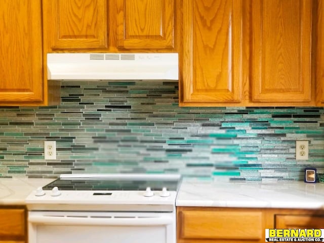 kitchen featuring tasteful backsplash, light stone counters, and white range