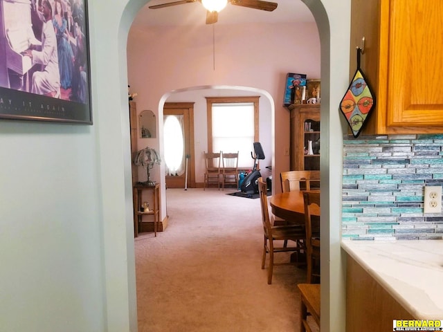 dining area with ceiling fan and light colored carpet