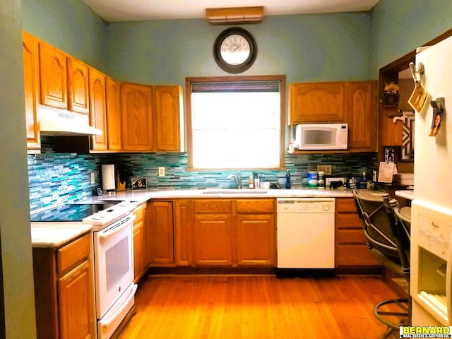 kitchen featuring decorative backsplash, sink, white appliances, and light hardwood / wood-style floors