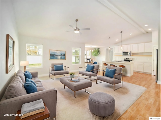 living room with ceiling fan, lofted ceiling with beams, a wealth of natural light, and light hardwood / wood-style floors