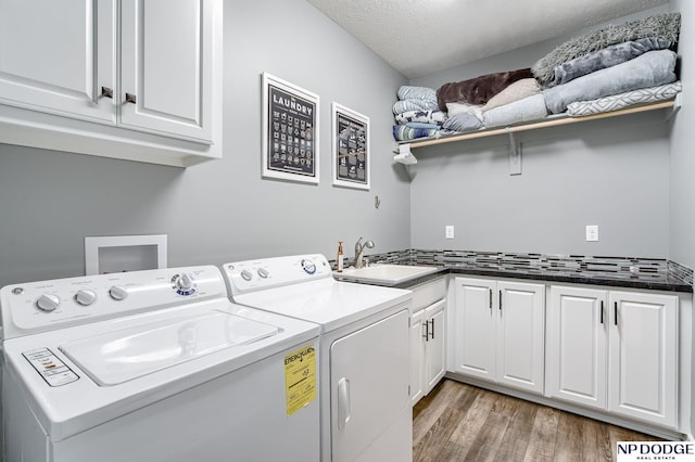 laundry area with sink, light hardwood / wood-style flooring, separate washer and dryer, a textured ceiling, and cabinets