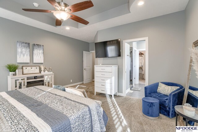 carpeted bedroom featuring ceiling fan and a tray ceiling