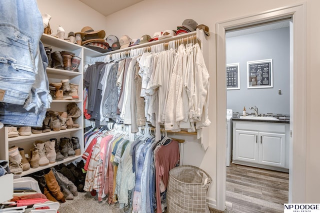 walk in closet featuring sink, washer / dryer, and light hardwood / wood-style flooring