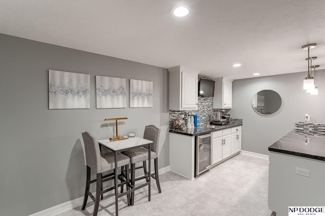 kitchen with backsplash, beverage cooler, pendant lighting, white cabinets, and a breakfast bar