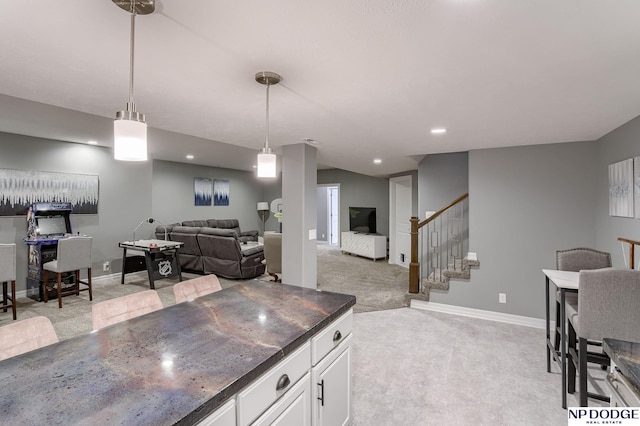 kitchen featuring pendant lighting, white cabinets, and light carpet