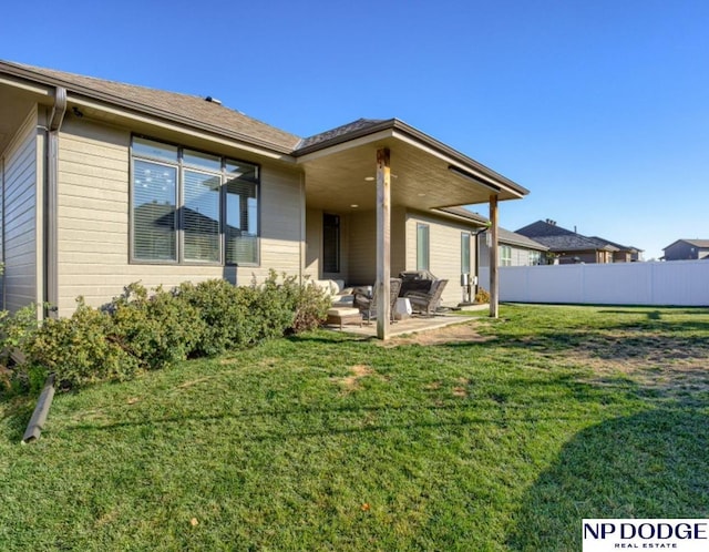 back of house with a lawn and a patio