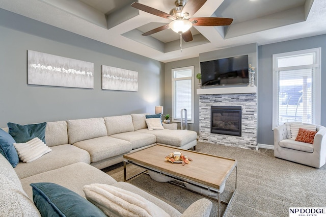 living room featuring coffered ceiling, a stone fireplace, ceiling fan, carpet, and a raised ceiling