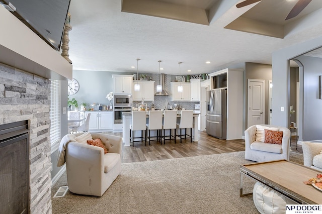 living room featuring ceiling fan, light colored carpet, a fireplace, and a textured ceiling