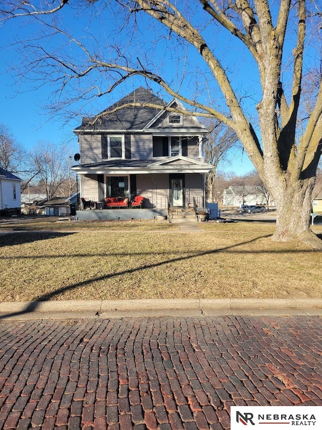 view of front of home with a front yard, covered porch, and cooling unit