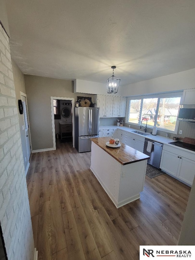 kitchen featuring decorative light fixtures, a kitchen island, sink, stainless steel appliances, and white cabinets