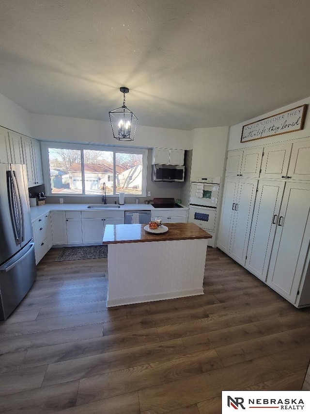 kitchen with a center island, pendant lighting, sink, white cabinetry, and appliances with stainless steel finishes