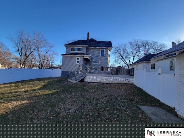 rear view of property with a deck and a yard