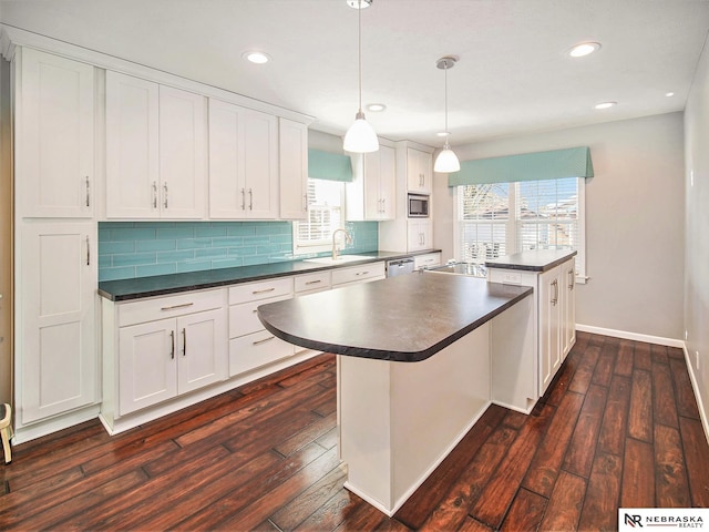 kitchen with a center island, pendant lighting, sink, white cabinetry, and dark wood-type flooring