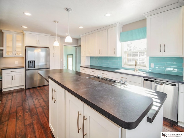 kitchen featuring pendant lighting, a kitchen island, sink, dark wood-type flooring, and stainless steel appliances