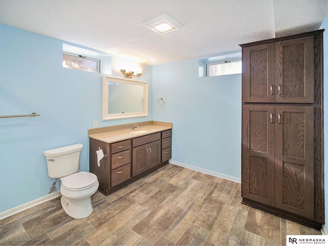 bathroom with a textured ceiling, toilet, vanity, and hardwood / wood-style floors