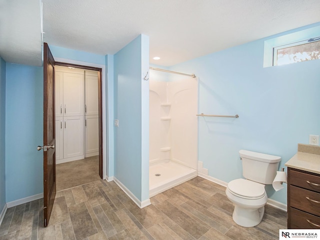 bathroom featuring toilet, vanity, a shower, and a textured ceiling