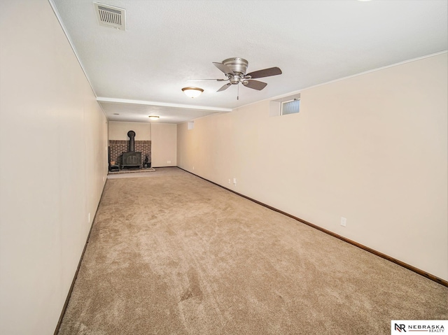 interior space with light colored carpet, a wood stove, and ceiling fan