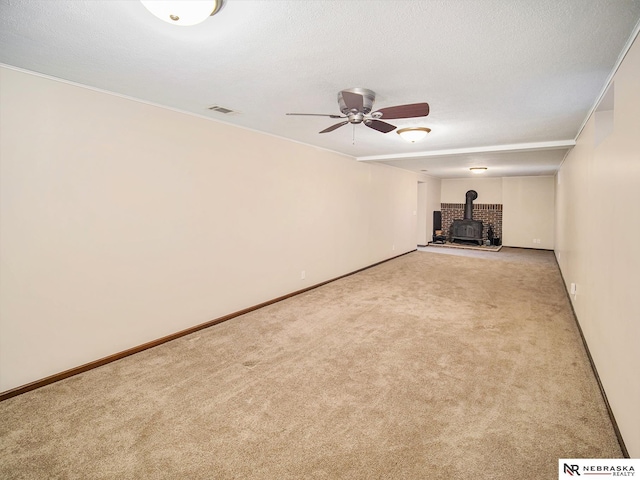 unfurnished living room featuring light carpet, ceiling fan, and a wood stove