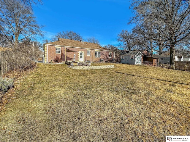 rear view of property featuring a storage unit and a yard