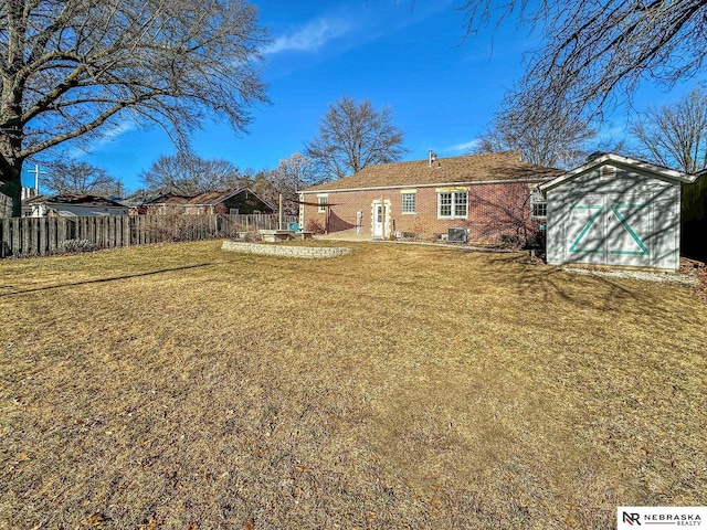 rear view of property featuring a storage unit and a yard