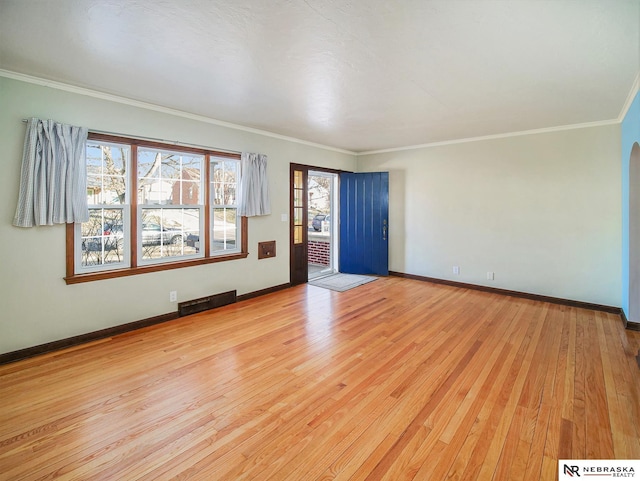 unfurnished room with ornamental molding and light wood-type flooring