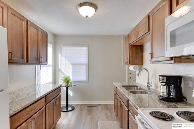 kitchen featuring light hardwood / wood-style floors, white appliances, light stone countertops, ornamental molding, and sink