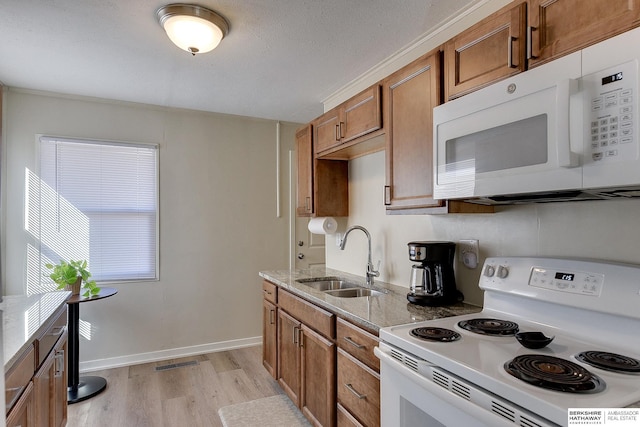 kitchen with light stone counters, sink, white appliances, and light hardwood / wood-style flooring