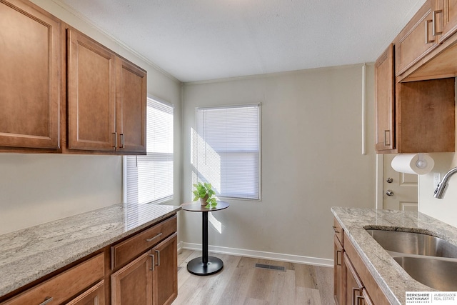 kitchen featuring sink, light stone counters, and light hardwood / wood-style floors