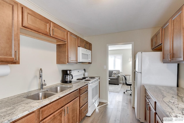 kitchen with light stone countertops, sink, white appliances, and light hardwood / wood-style flooring