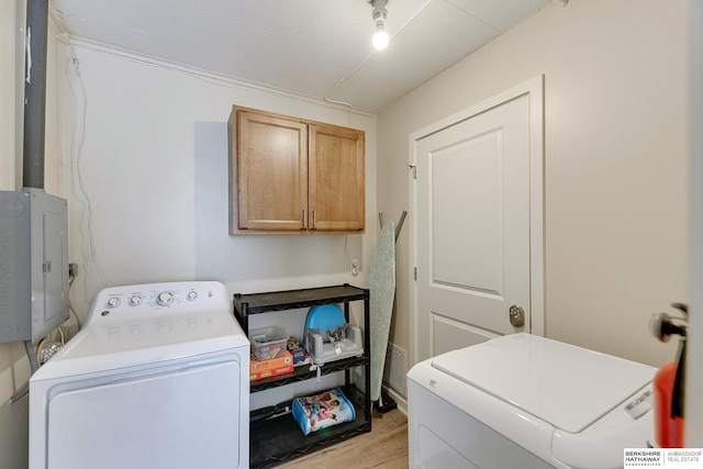 clothes washing area featuring cabinets, electric panel, light hardwood / wood-style floors, and washing machine and clothes dryer