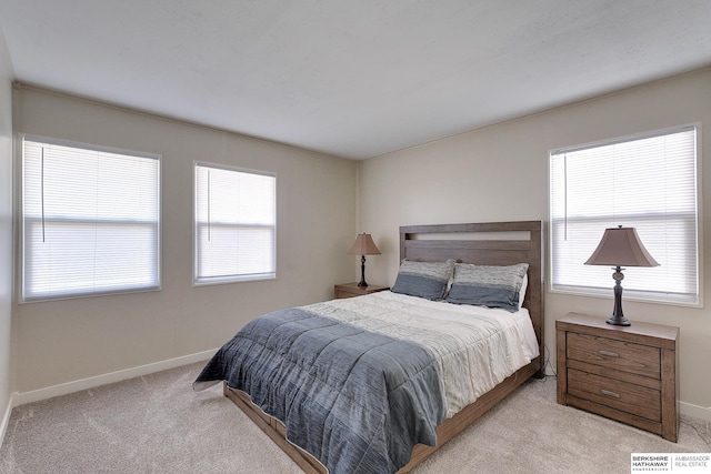 bedroom featuring light colored carpet and multiple windows