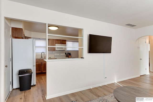 kitchen featuring sink, white appliances, and light hardwood / wood-style flooring