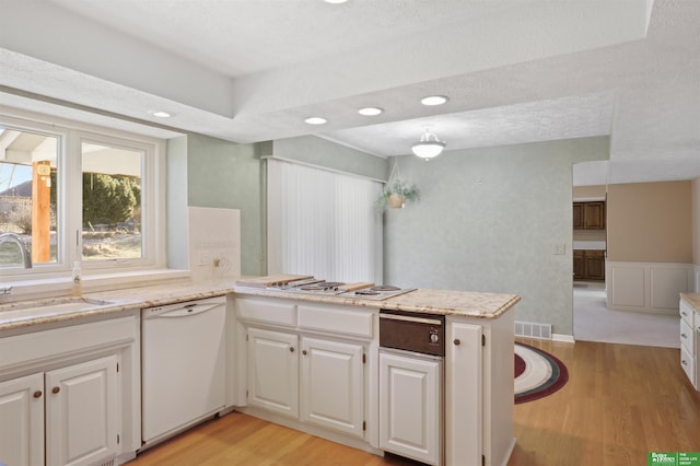 kitchen featuring kitchen peninsula, sink, white appliances, white cabinetry, and light hardwood / wood-style flooring