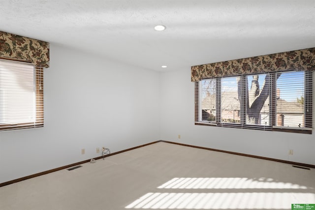 carpeted spare room featuring a textured ceiling