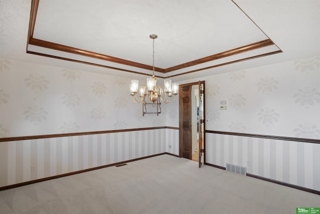 spare room featuring a tray ceiling, ornamental molding, and a notable chandelier