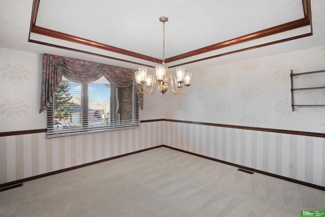 carpeted empty room featuring ornamental molding, a raised ceiling, and an inviting chandelier