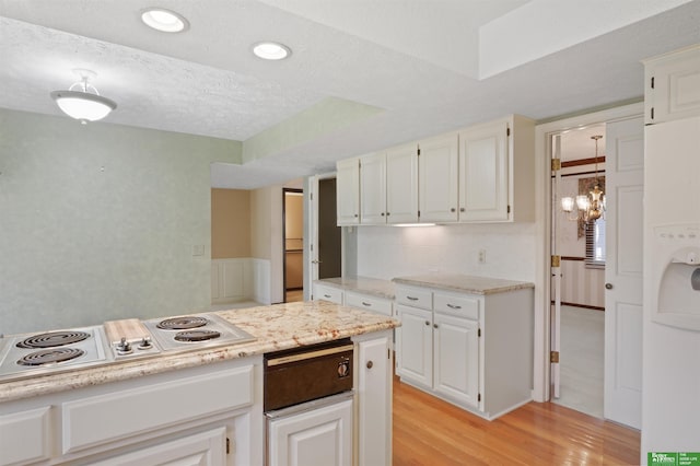 kitchen with a textured ceiling, light hardwood / wood-style floors, white cabinets, and white electric stovetop