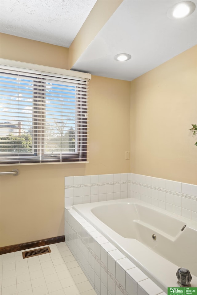 bathroom with tile patterned flooring and tiled tub