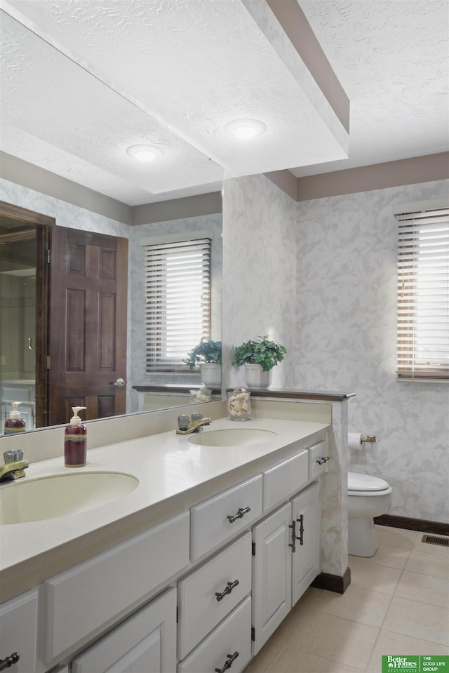 bathroom featuring toilet, vanity, plenty of natural light, and tile patterned floors